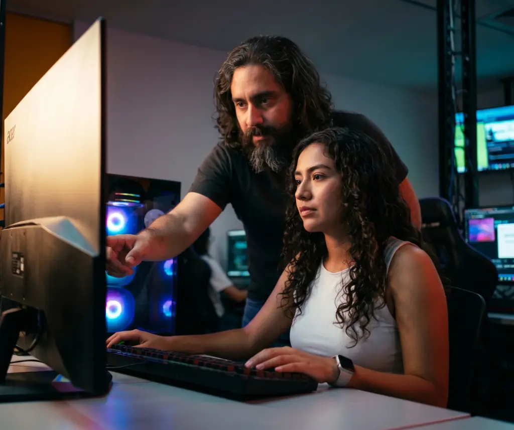 Docente guiando a una estudiante en un proyecto digital de videojuegos
